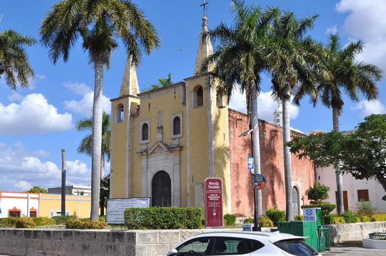Catholic church with Roystonea regia palm trees in the corner of the Parque de Santa Ana, Merida, Yucatan, Mexico